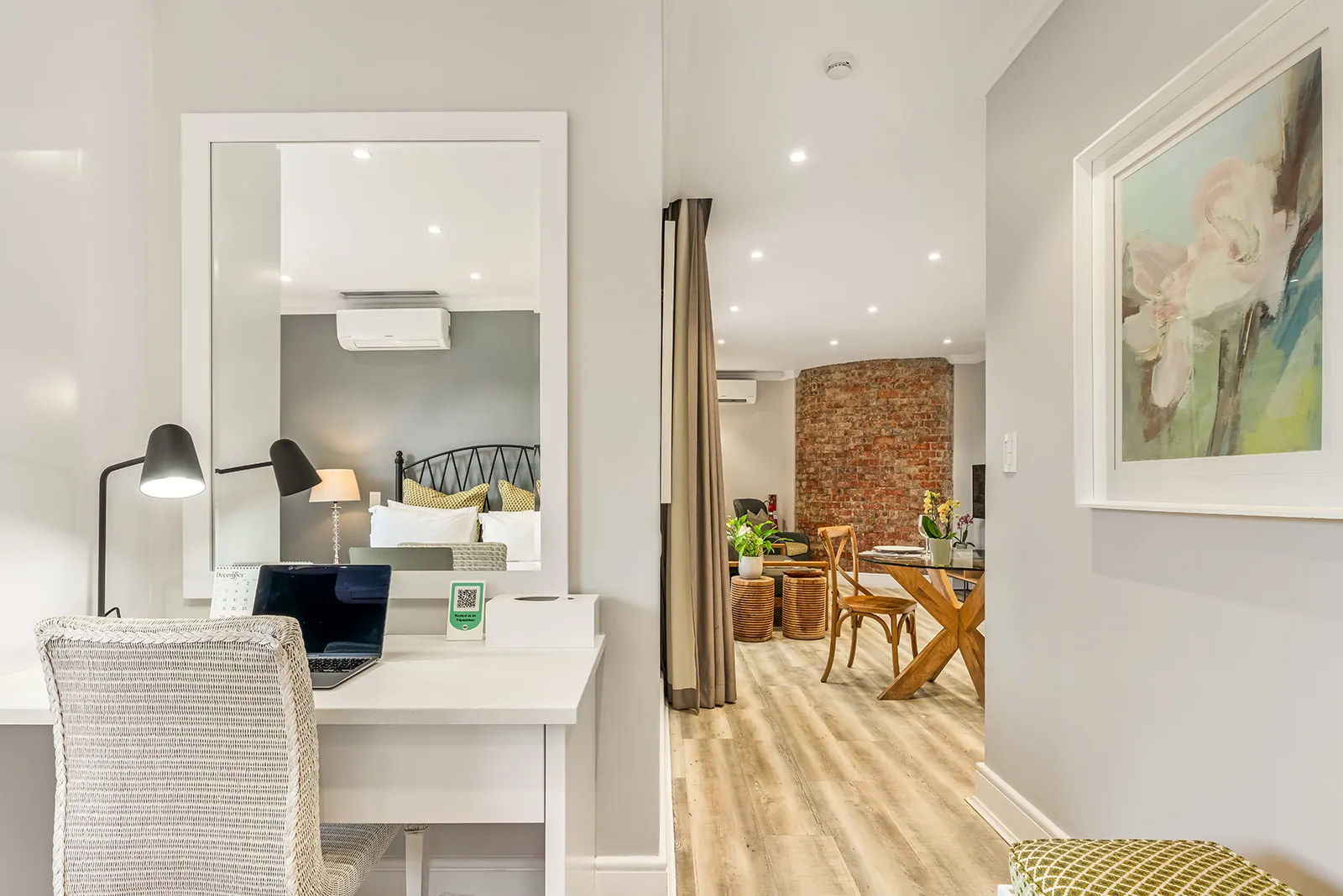 Work-from-suite desk with mirror, opening into the lounge with brick feature wall | Studio Stay on Sixty6 boutique hotel & accommodation in Sandton